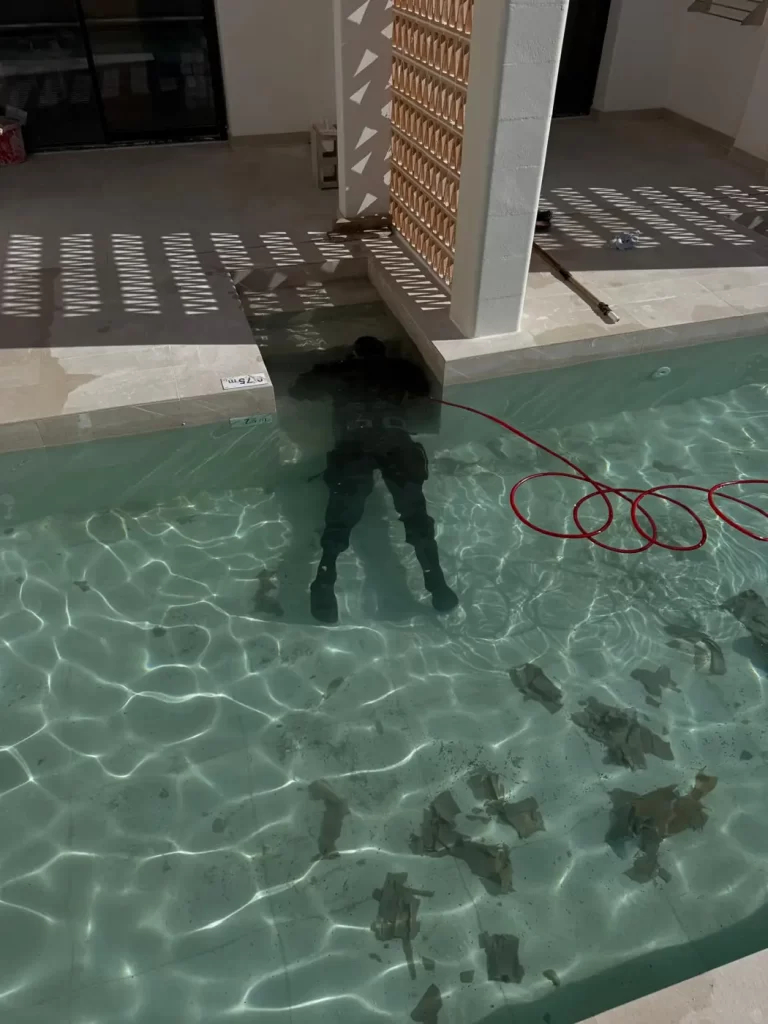 Técnico sumergido localizando una fuga junto a la pared de la piscina