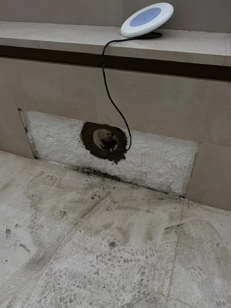 Foco de piscina desmontado para reparar la fuga en su pasamuros